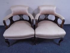 A pair of Edwardian mahogany low tub chairs upholstered in striped fabric.