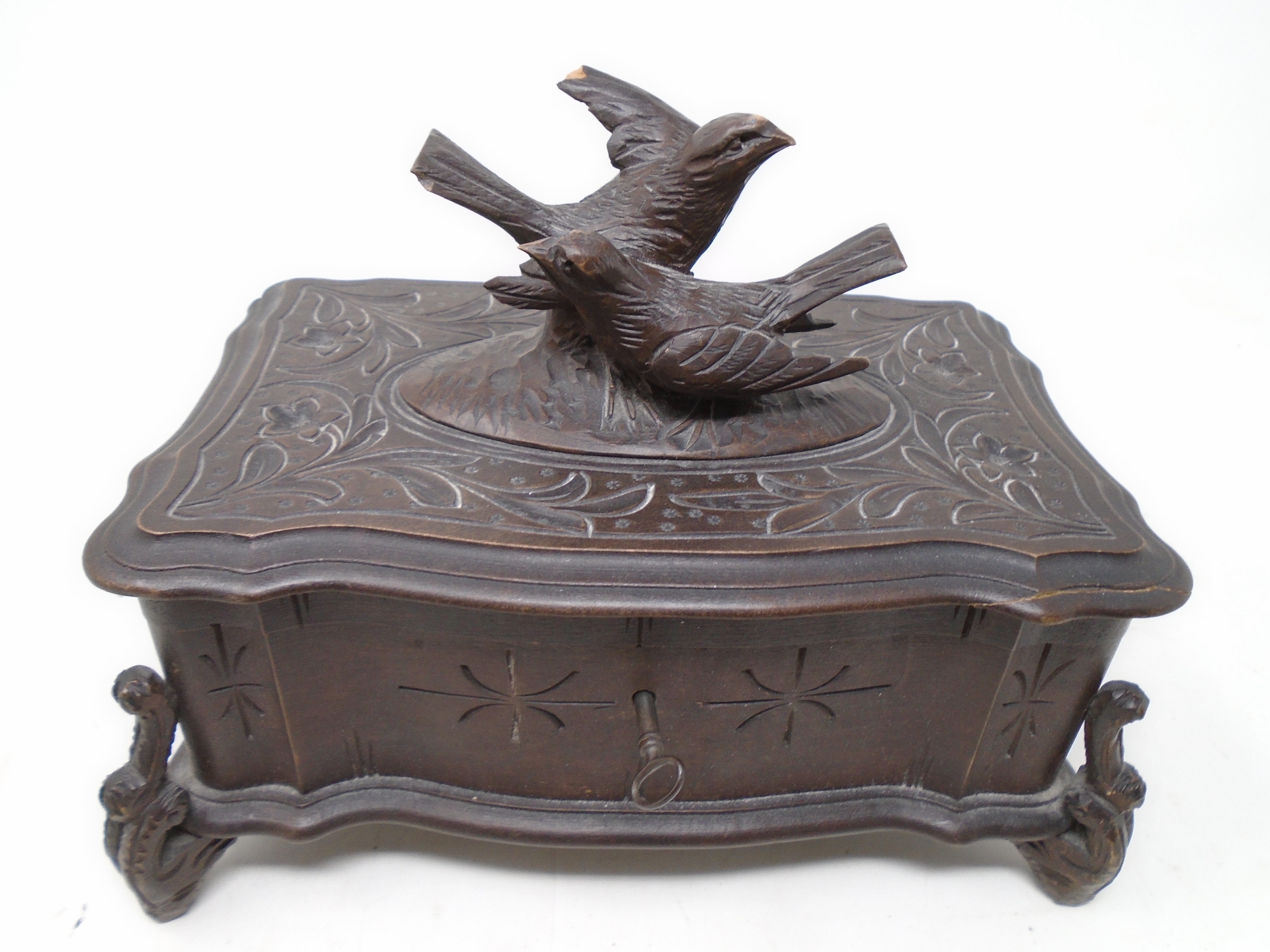 A carved Black Forest musical jewellery casket surmounted by two birds.