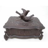 A carved Black Forest musical jewellery casket surmounted by two birds.