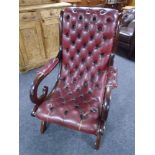 A stained beech scroll armchair upholstered in Burgundy buttoned and studded leather.