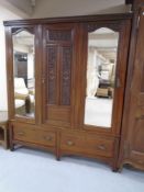 A 19th century mahogany triple door wardrobe fitted with mirrors and two drawers beneath,