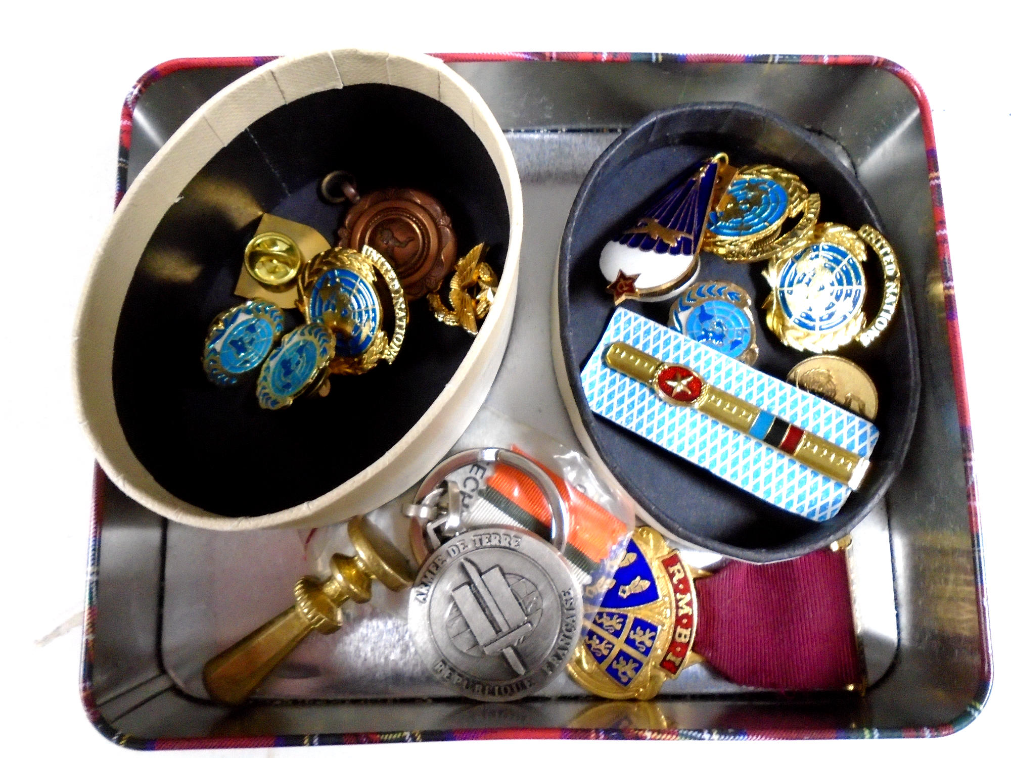 A tin containing United Nations enamelled badges, Steward medal, brass seal,