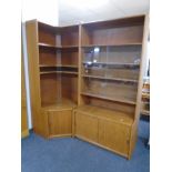 A 20th century teak two piece corner book case fitted with cupboards below.
