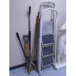 Two sets of folding steps together with a bundle of assorted garden tools.