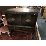 An Edwardian carved oak four door sideboard on raised legs fitted with drawers beneath.