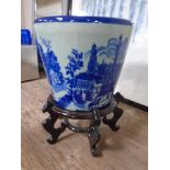 A blue and white glazed ceramic ironstone planter on a wooden stand.