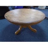 A circular oak pedestal coffee table.