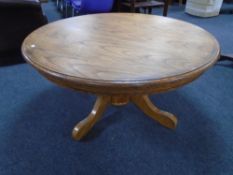 A circular oak pedestal coffee table.
