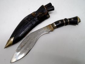 A Kukri knife in leather sheath.