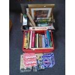 Two boxes containing enamelled wall signs, assorted games, hardcover books, prints etc.