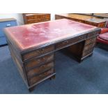 A mahogany nine drawer twin pedestal partners desk with red tooled leather inset panel,