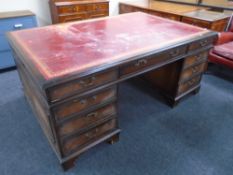 A mahogany nine drawer twin pedestal partners desk with red tooled leather inset panel,