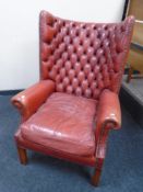 A red buttoned and studded leather Chesterfield wingback armchair.