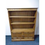 An Ercol Grasmere solid elm and beech bookcase fitted with cupboards beneath,