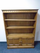 An Ercol Grasmere solid elm and beech bookcase fitted with cupboards beneath,