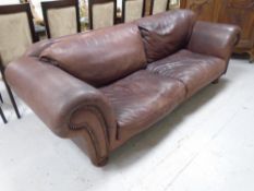 A brown leather scroll arm settee.