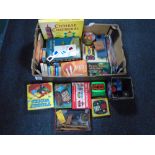 A box containing assorted toys and games including playing cards, board games, Rubiks cube,