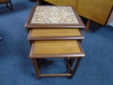A nest of three mid-20th century teak G-Plan tables one with tiled inset panel.