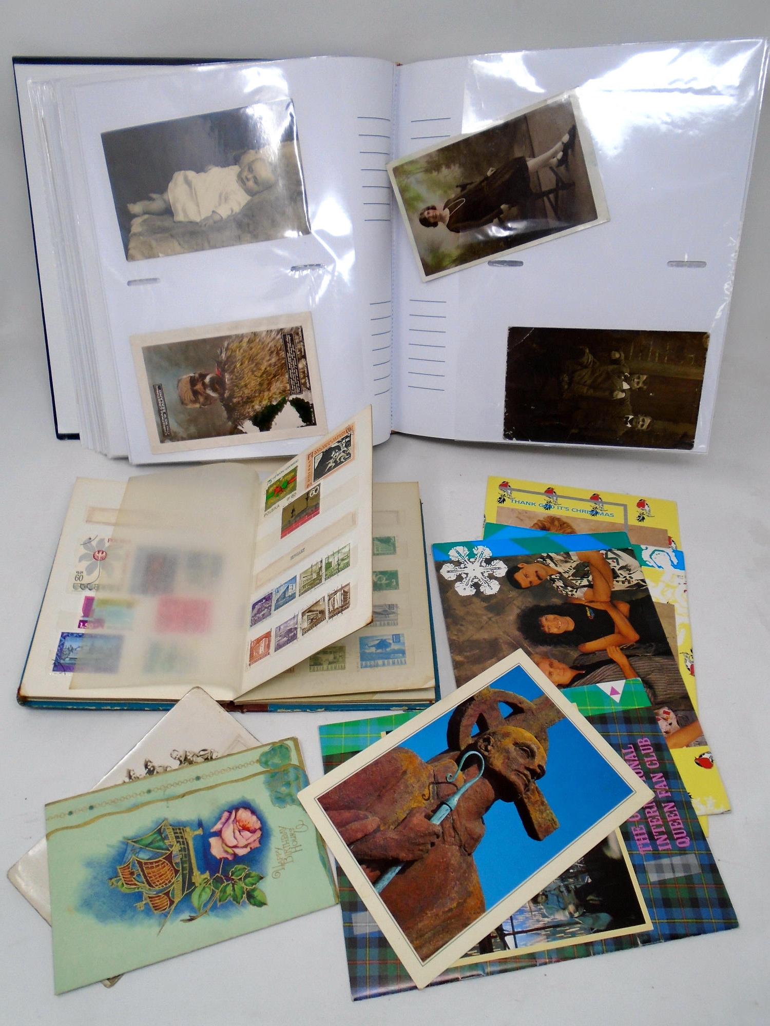 A tray containing an album of antiquarian and later postcards, a stamp album of world stamps etc.