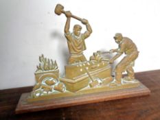 A brass door stop depicting blacksmiths.