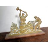 A brass door stop depicting blacksmiths.