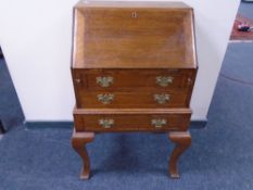 An Edwardian oak lady's bureau fitted with three drawers on raised legs.