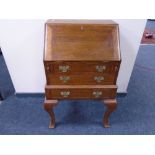 An Edwardian oak lady's bureau fitted with three drawers on raised legs.