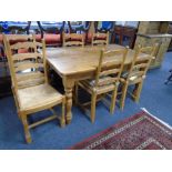 A pine farmhouse kitchen table together with a set of six rush seated ladder back chairs.
