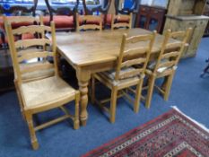 A pine farmhouse kitchen table together with a set of six rush seated ladder back chairs.