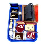 A tray containing carved wooden trinket boxes, leather purses, wristwatches, costume brooches,