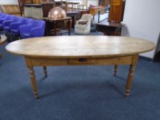 An antique pine oval farmhouse kitchen table fitted with a drawer,
