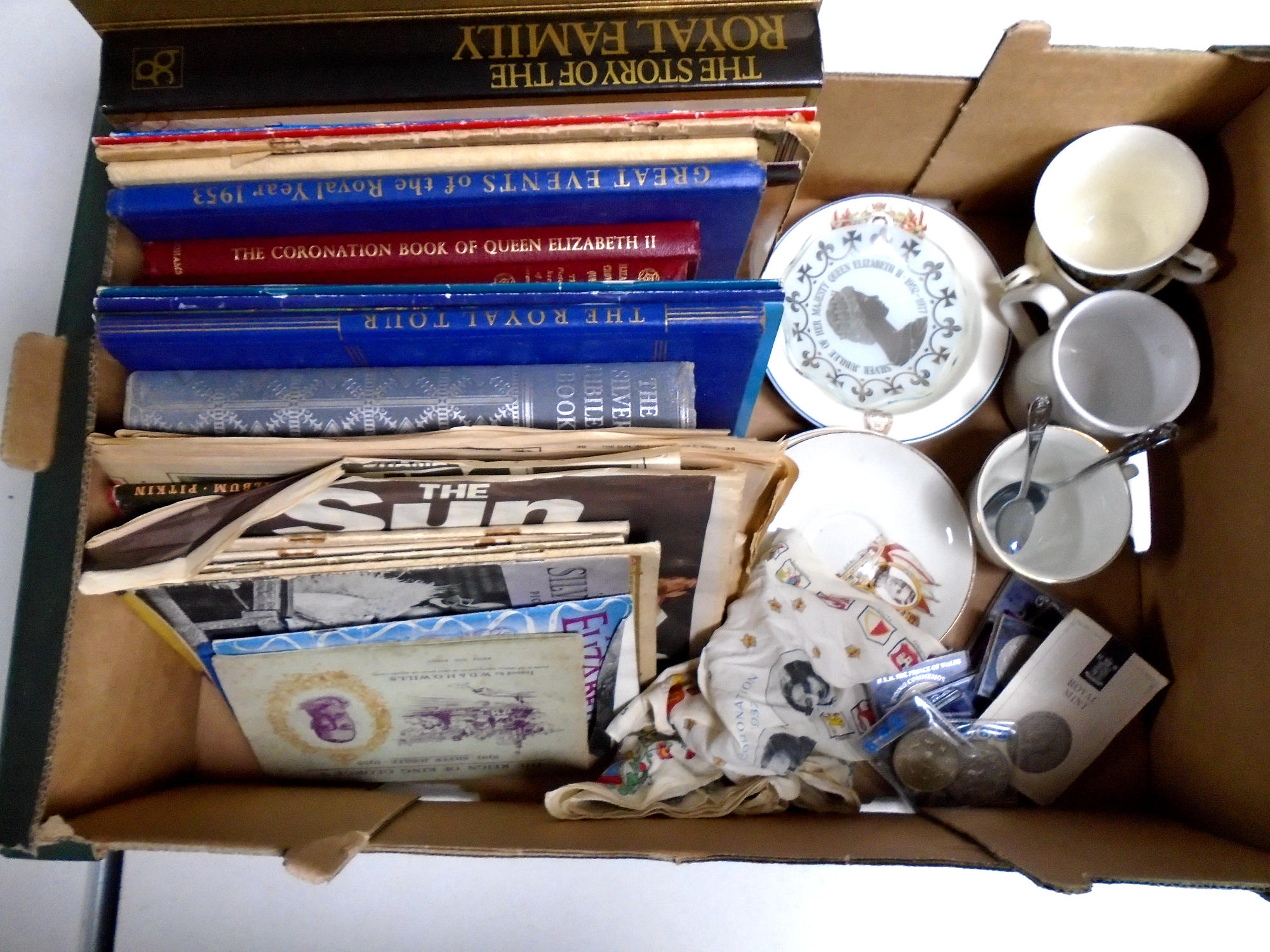 A box containing commemorative items including tea ware, crowns, coronation handkerchief,