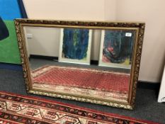 An over mantel mirror bevel-edged mirror in ornate gilt composition frame, 70cm by 100cm.