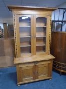 An oak Arts & Crafts double door bookcase fitted with cupboards and doors