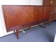 A mid-20th century teak four door high sideboard on raised legs fitted with four drawers beneath.