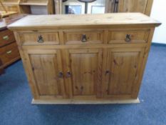 A Mexican pine triple door sideboard fitted with three drawers.