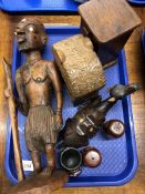 A tray containing a carved African tribal figure depicting a man with a walking stick,