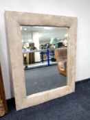 A bevel edge mirror in contemporary frame upholstered in a suede fabric (diameter 106cm).