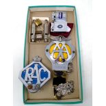 A box containing vintage AA and RAC badges, ACME whistles, Colibri and Firefly lighters.