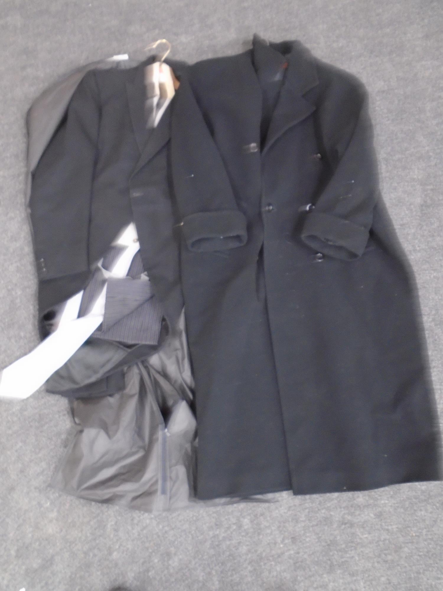 A gentleman's three piece suit with tie together with a gentleman's black full length coat.