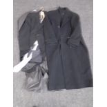 A gentleman's three piece suit with tie together with a gentleman's black full length coat.