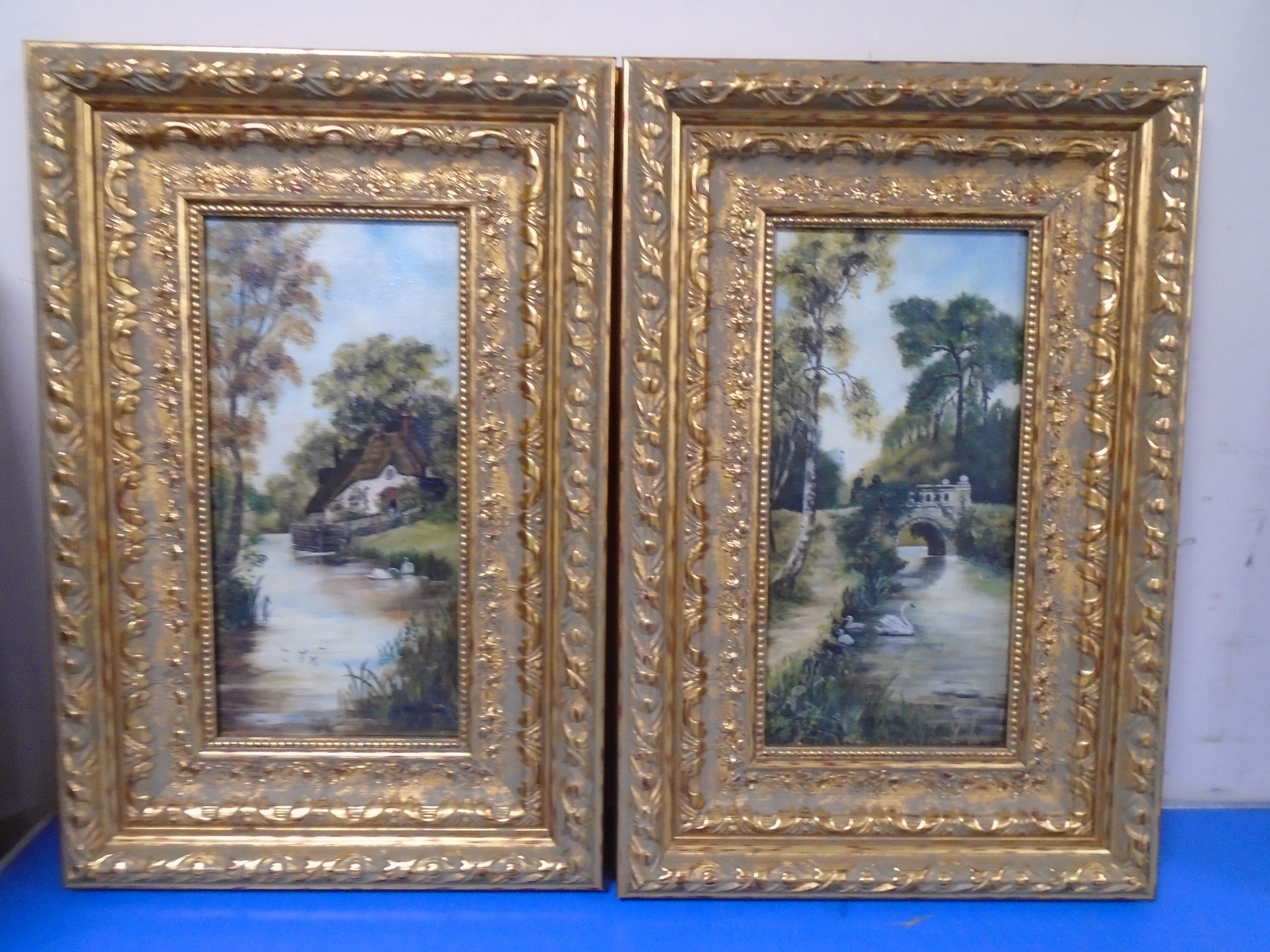 A pair of gilt frame oil-on-canvasses depicting swans on a lake.