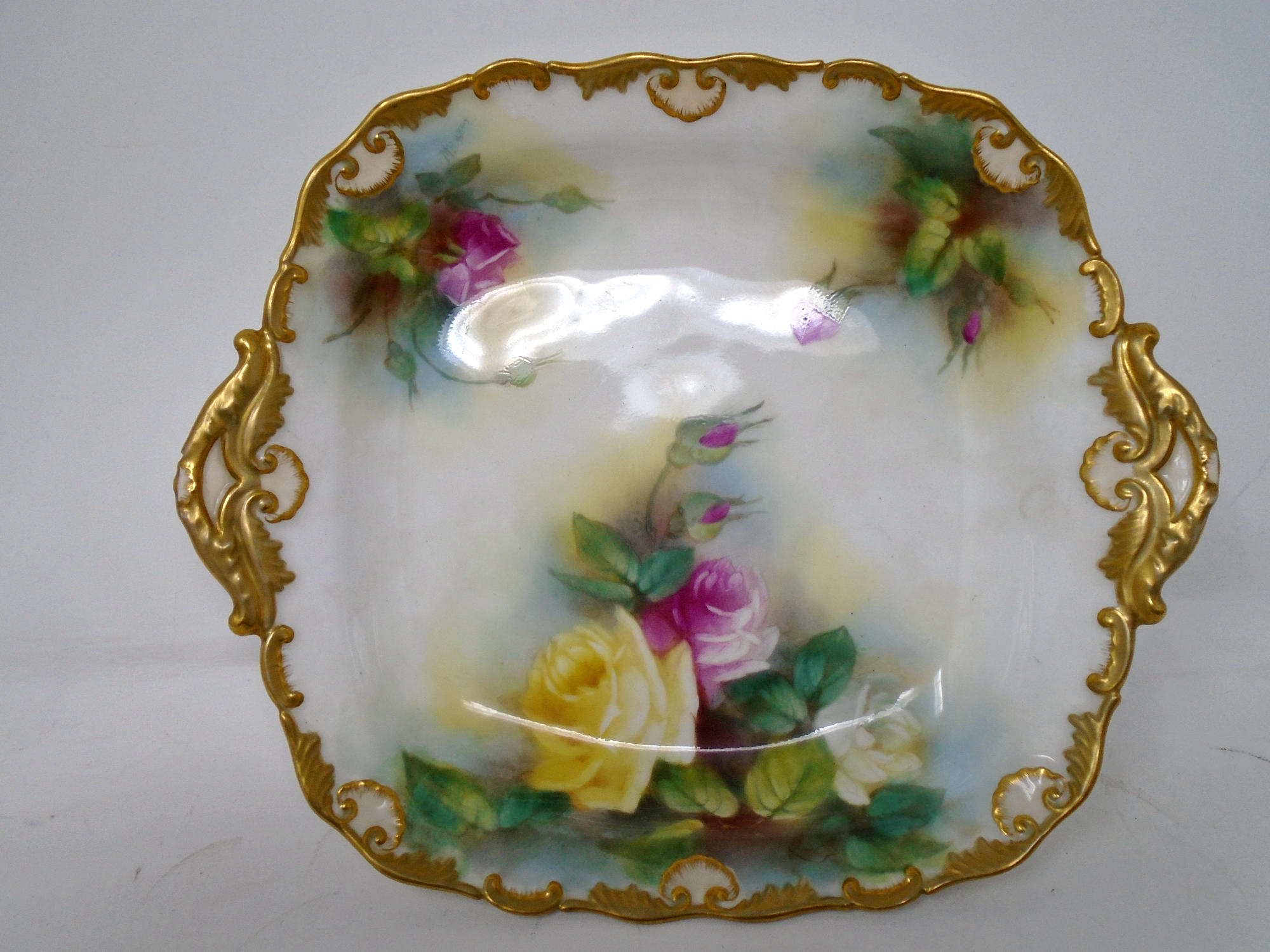 A Royal Worcester gilded twin handled dish decorated with roses.