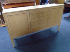 A Scandinavian double door sideboard fitted five central drawers on raised legs in pine finish