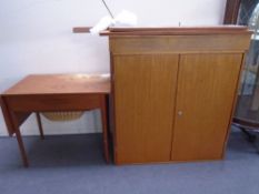 A mid-20th century teak flap sided sewing table together with a double door cabinet and a wall