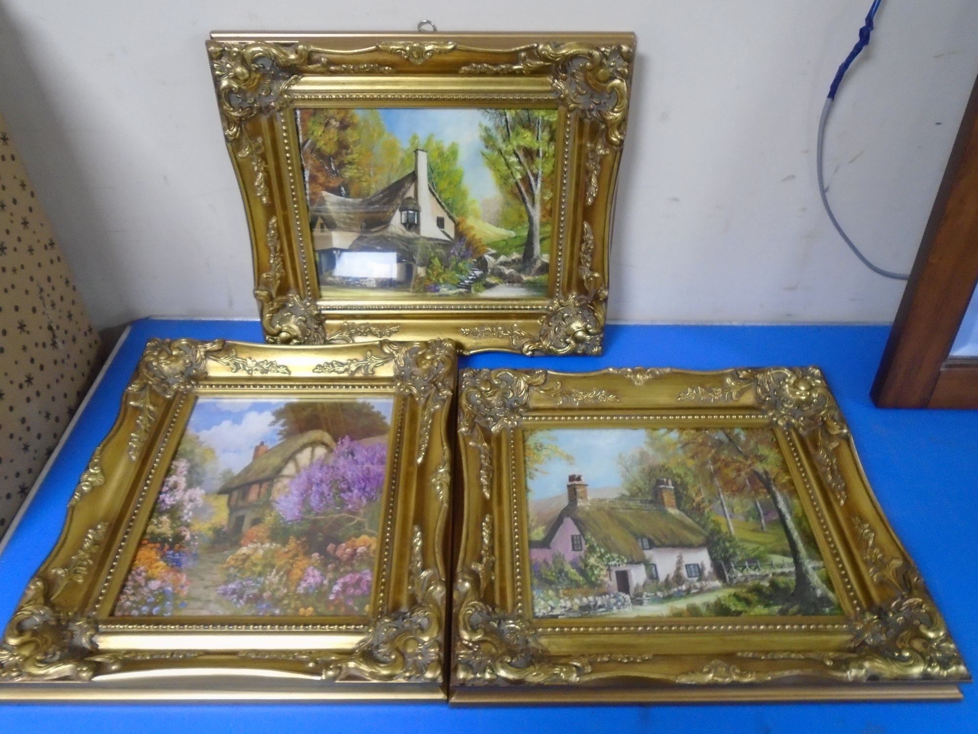 Two gilt frame oil-on-boards and one print depicting houses amongst trees.