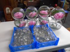 Eight glass fishbowl table centrepieces together with two crates containing storage jars and tea