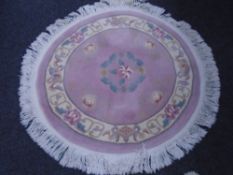 A Chinese circular fringed rug on pink ground