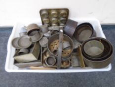 A box containing vintage kitchenalia including muffin dishes, cake tins, press, pipe funnels etc.