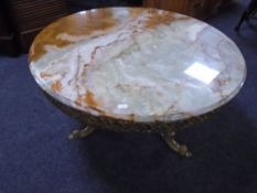 A circular onyx coffee table on gilt metal three way pedestal, diameter 79 cm.